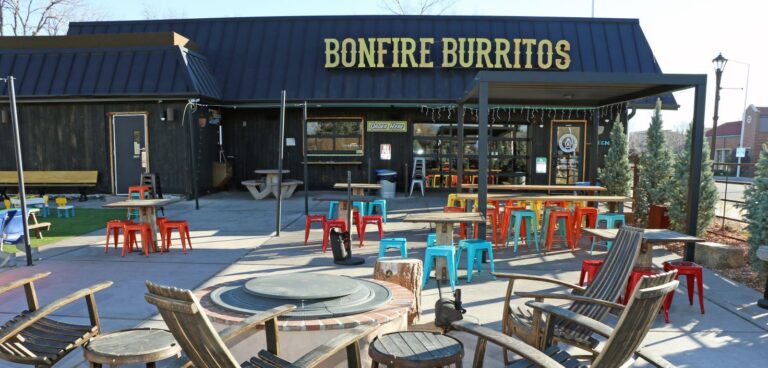 Chairs and fire pit set up in front of brown building with Bonfire Burritos sign