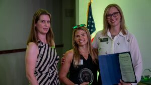 Three people smiling with an award