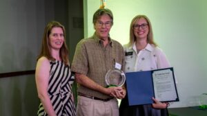 Three people smiling with an award