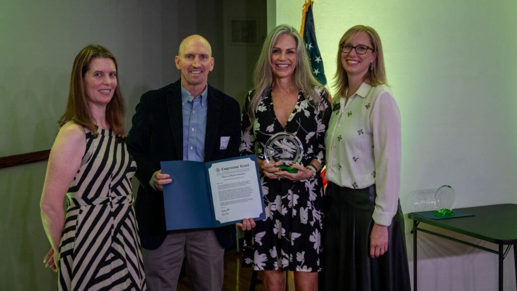 Three people smiling with an award