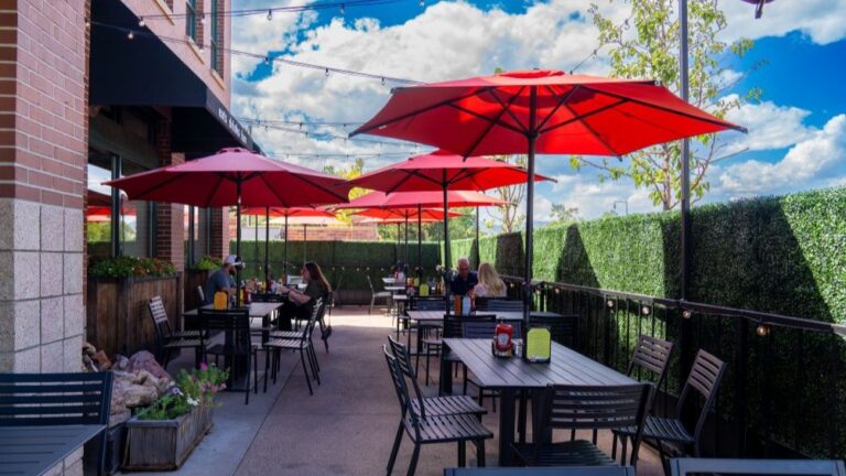 Bright red umbrellas over table on a patio with greenery