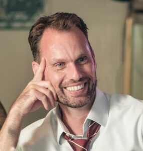 Man smiling resting his chin in his hand