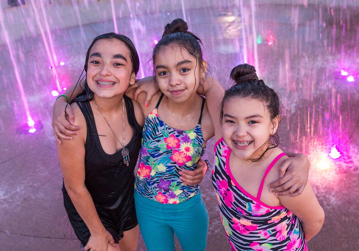 Three young girls playing in the water at a splash pad